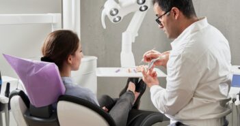 Zahnarzt erklärt seiner Patientin in der Praxis den Ablauf einer Wurzelbehandlung
